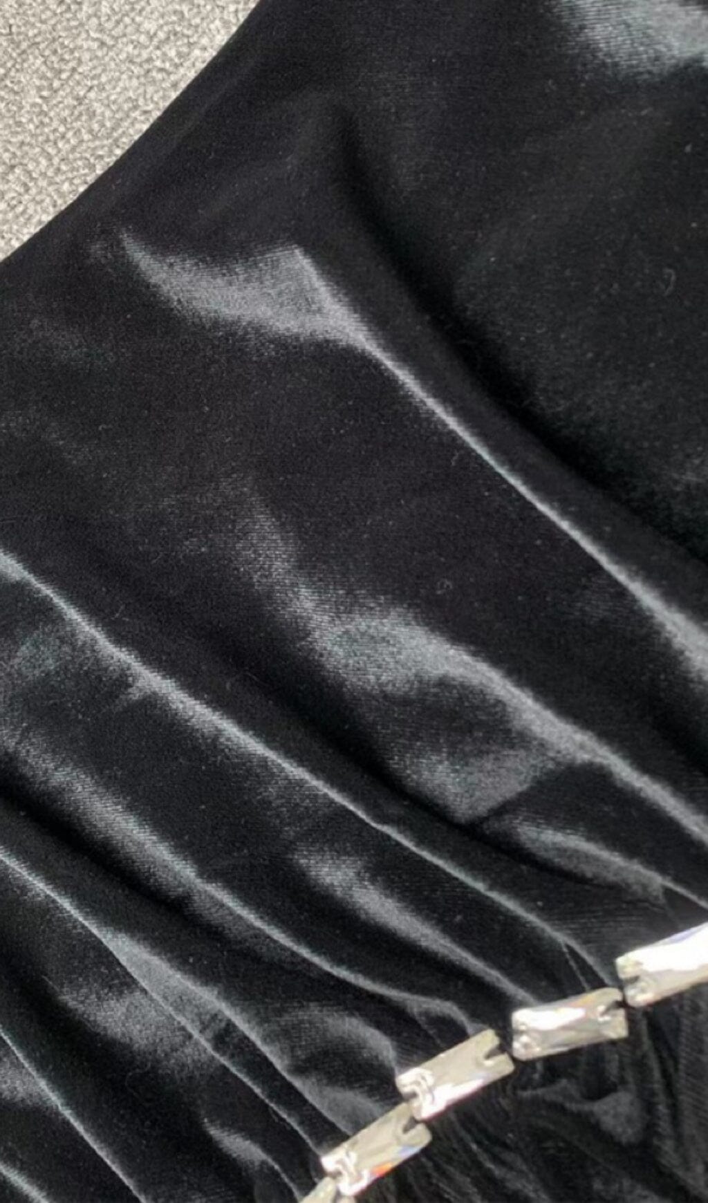 Vestido largo de terciopelo negro con un hombro al descubierto y diamantes